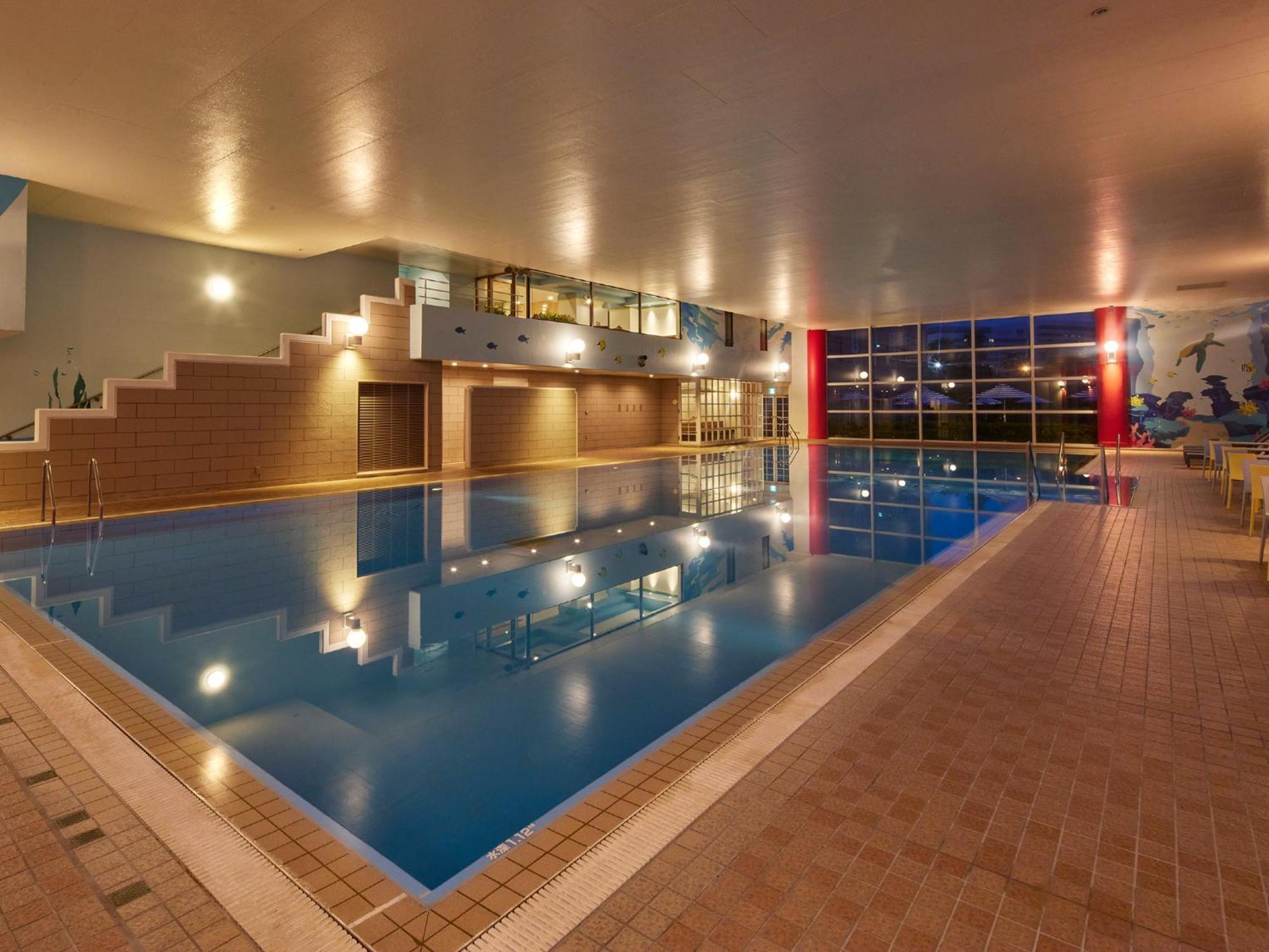 Grand Nikko Tokyo Bay Maihama Hotel Urayasu Екстериор снимка The photo shows an indoor swimming pool area. The pool features a calm blue water surface and is surrounded by tiled flooring. There is a staircase leading to a higher level, likely providing access to a lounge or seating area. Large windows allow na