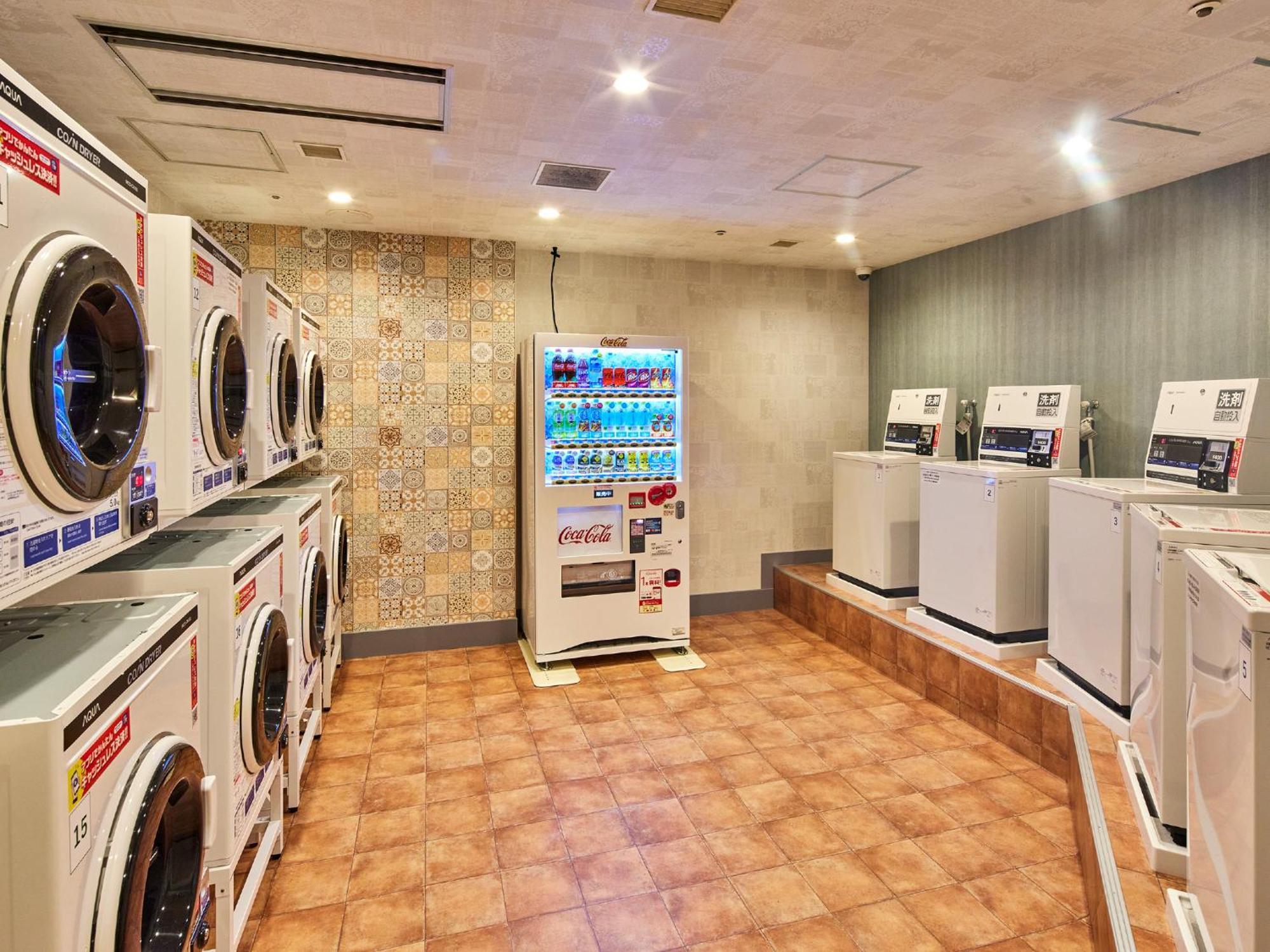 Grand Nikko Tokyo Bay Maihama Hotel Urayasu Екстериор снимка The photo shows a laundry room equipped with several washing machines and dryers. On the left side, there are multiple front-loading washing machines arranged in a row, and on the right side, there are dryers. In the center, there is a vending machin